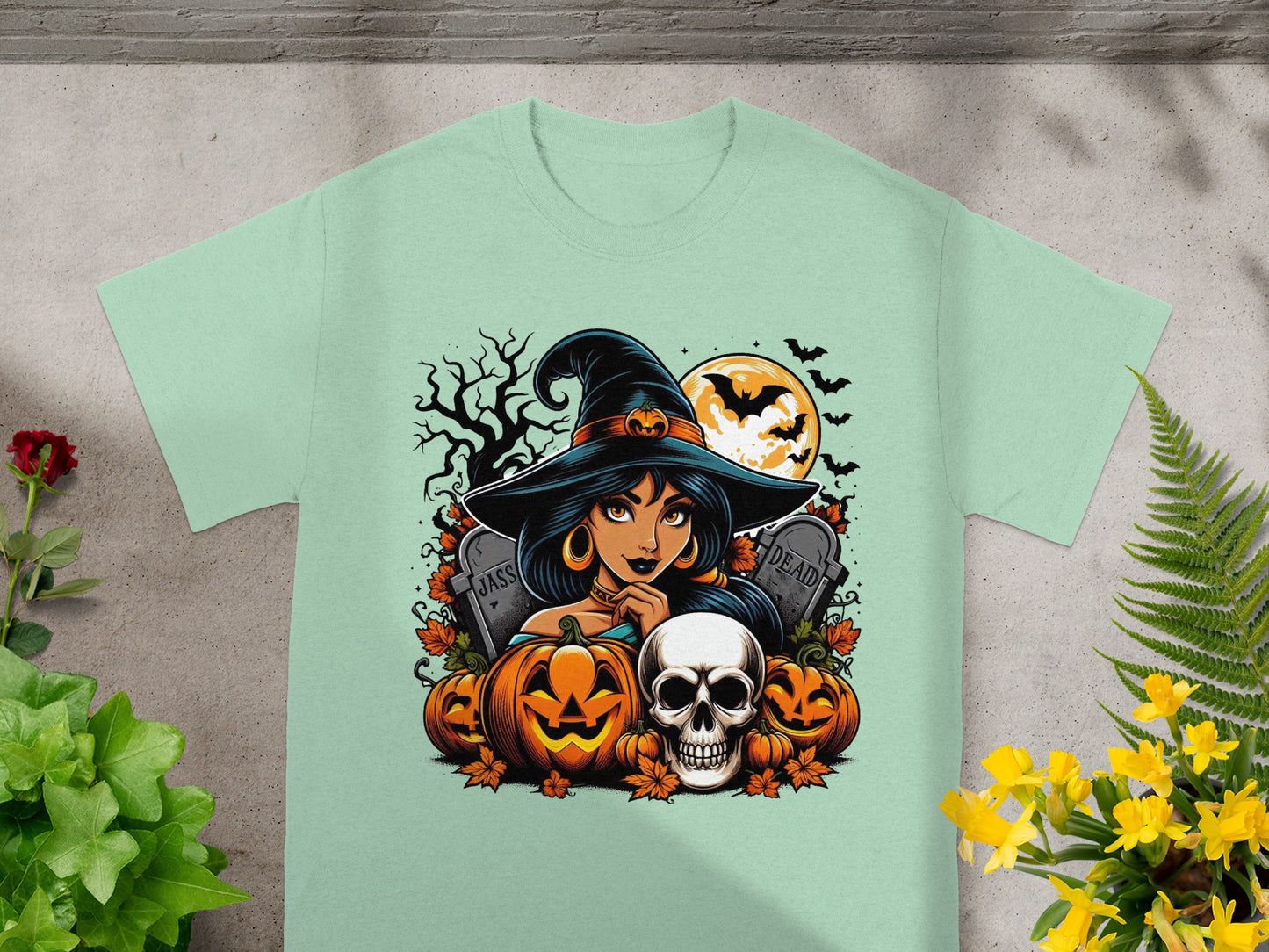 Halloween t-shirt design featuring a witch, pumpkins, skull, gravestones, and bats.