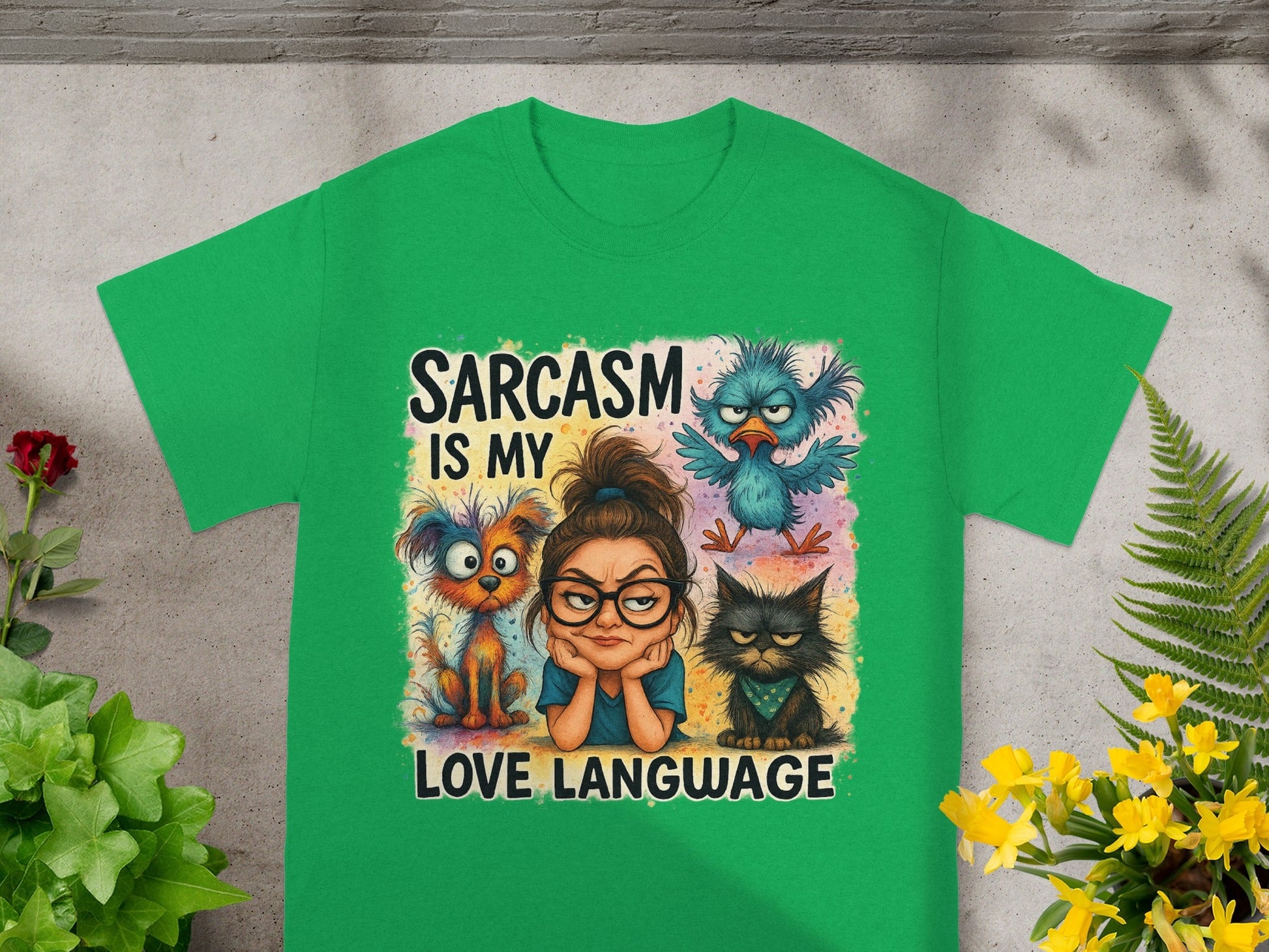 Green t-shirt with a woman, dog, cat, and bird illustration and "Sarcasm is my love language" text.