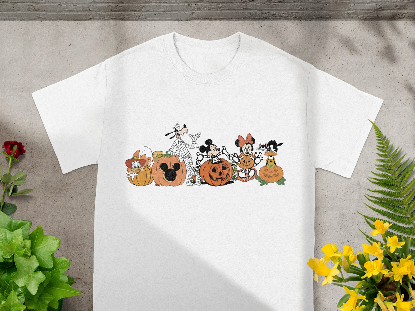 White t-shirt with Disney characters and pumpkins in a Halloween theme.