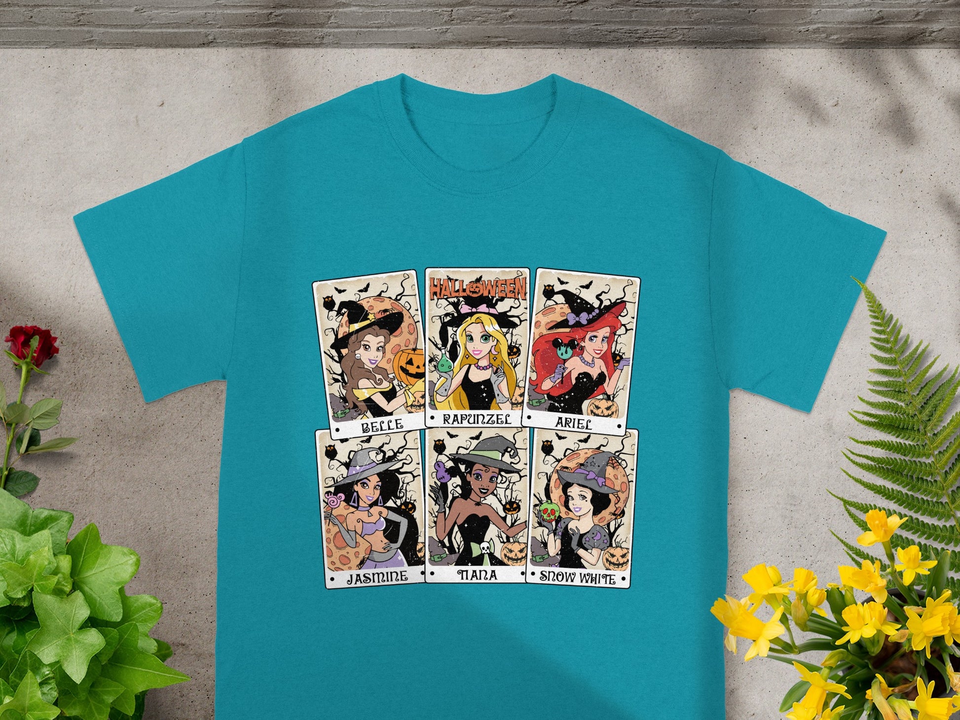Six Halloween-themed Disney princess illustrations in tarot card style on a teal t-shirt.