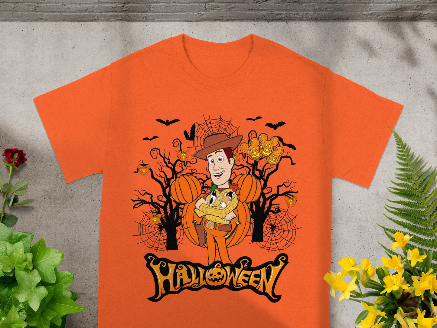 Orange t-shirt with Woody character holding pumpkins and Mickey Mouse heads, Halloween theme.