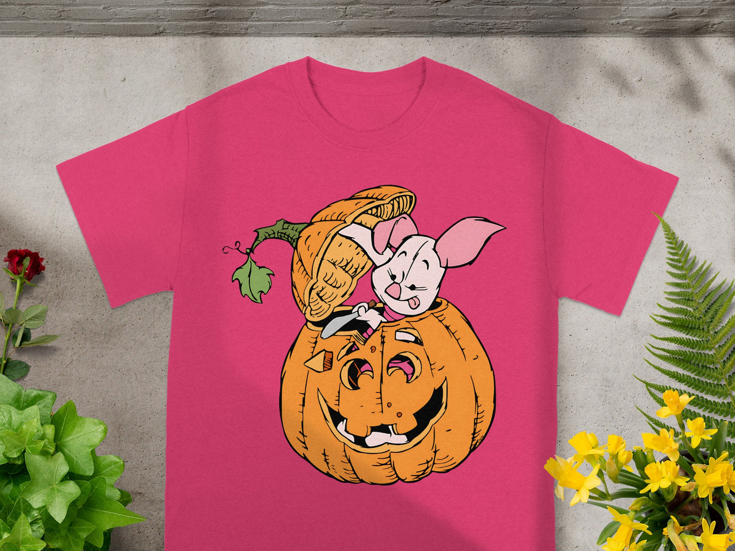 Piglet peeking out of a jack-o'-lantern on a pink t-shirt.