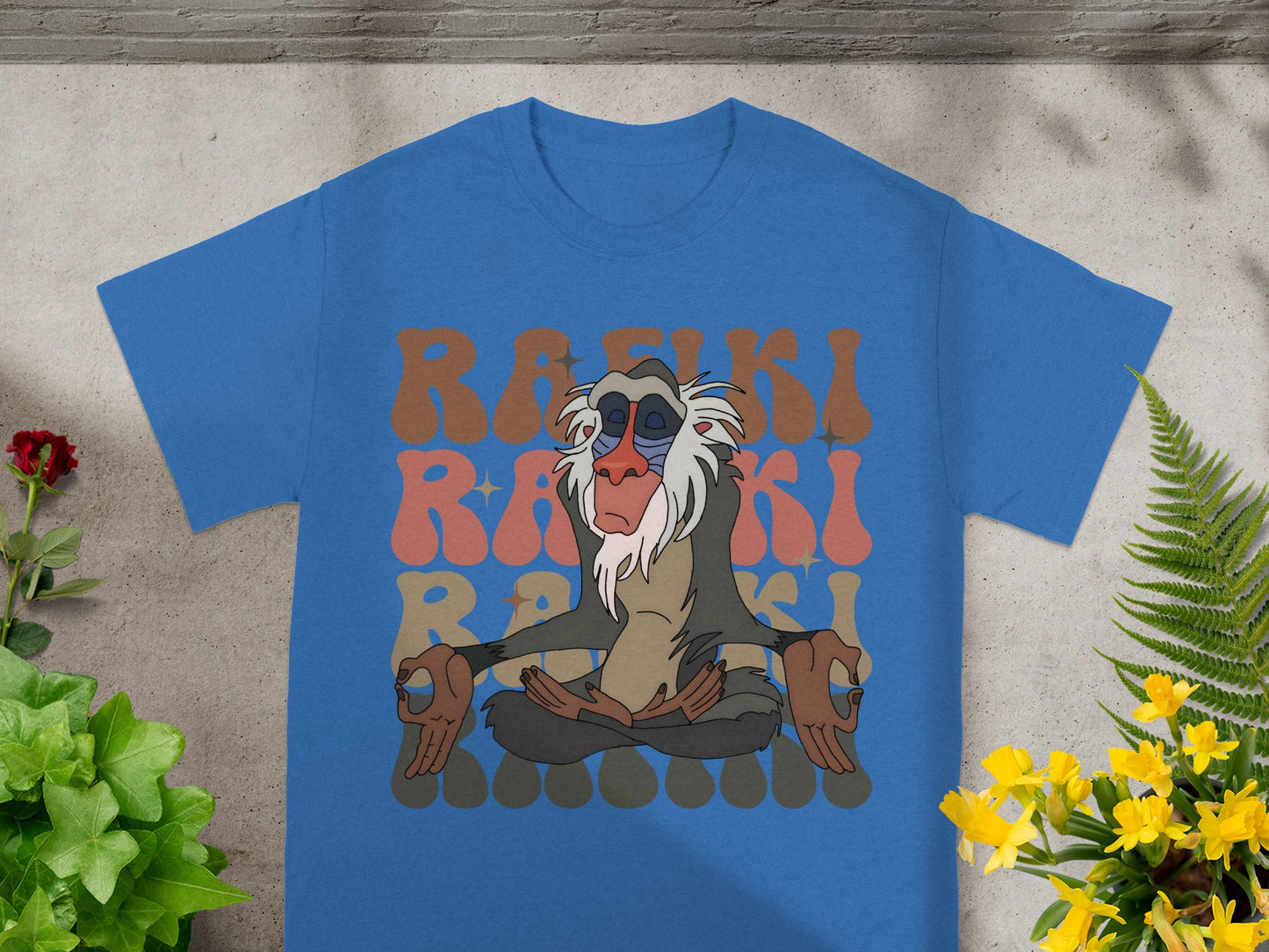 Rafiki meditating on a blue t-shirt with brown text.