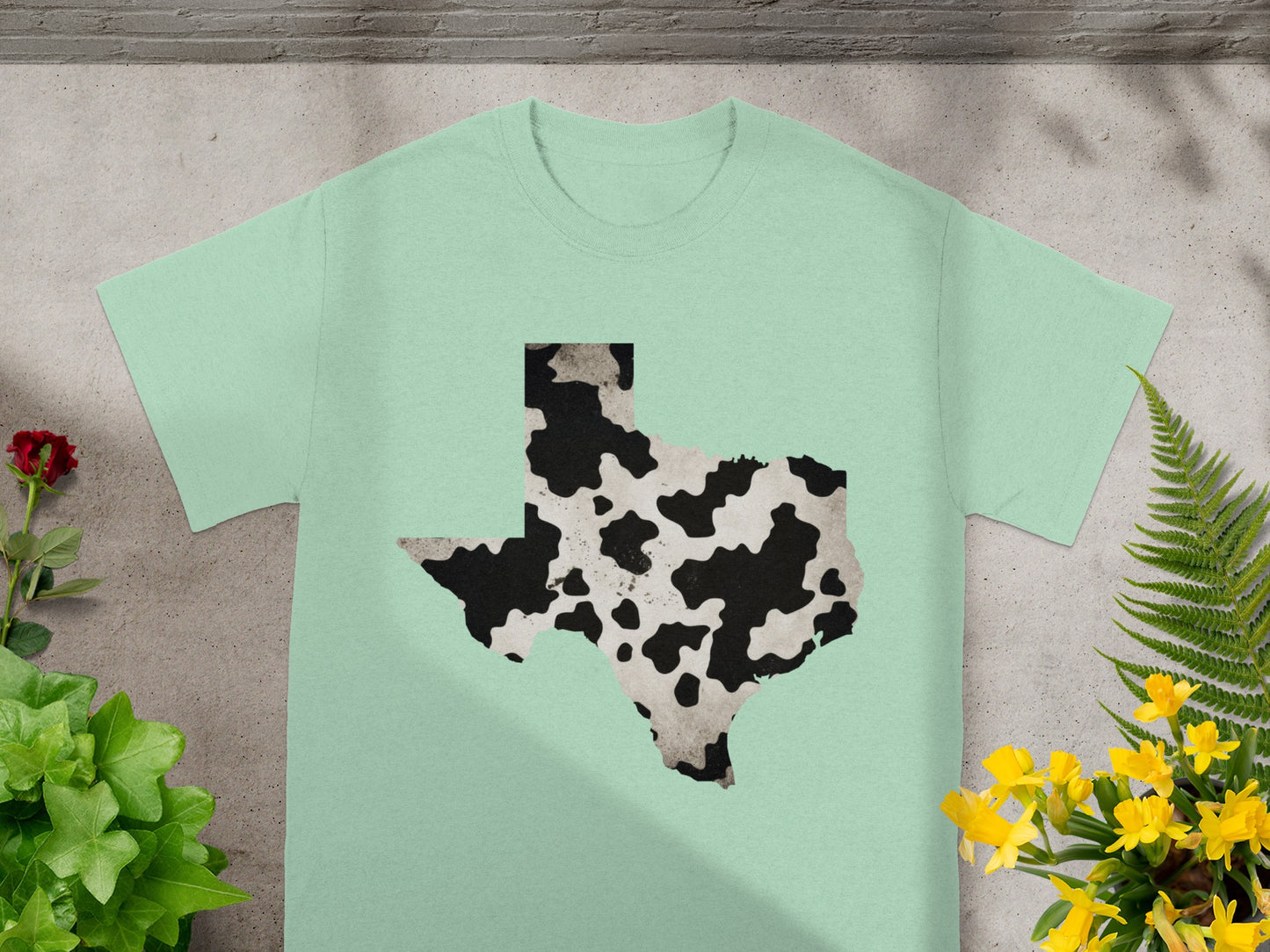Light green t-shirt with Texas outline in cow print pattern.