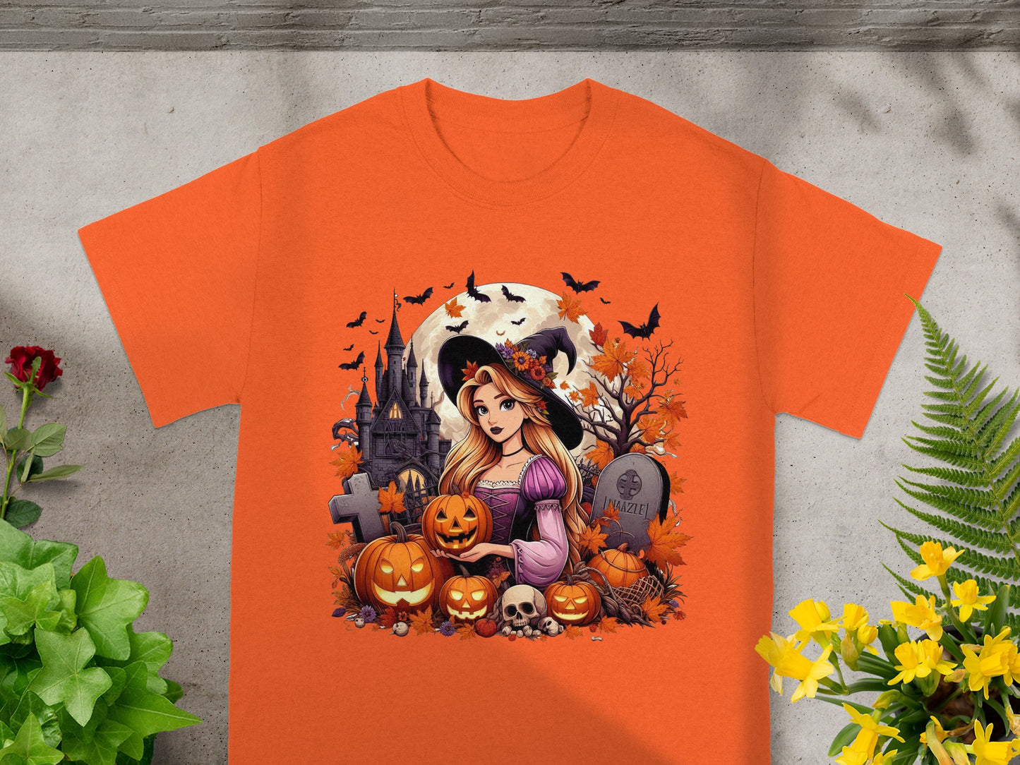 Orange t-shirt with Halloween graphic of witch, castle, pumpkins, bats, and tombstone.