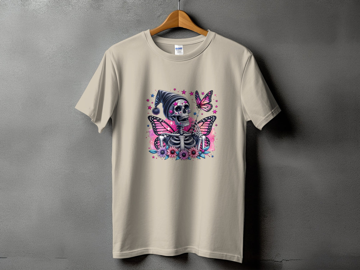 Skeleton with butterfly wings, flowers, and stars graphic on a light tan t-shirt.