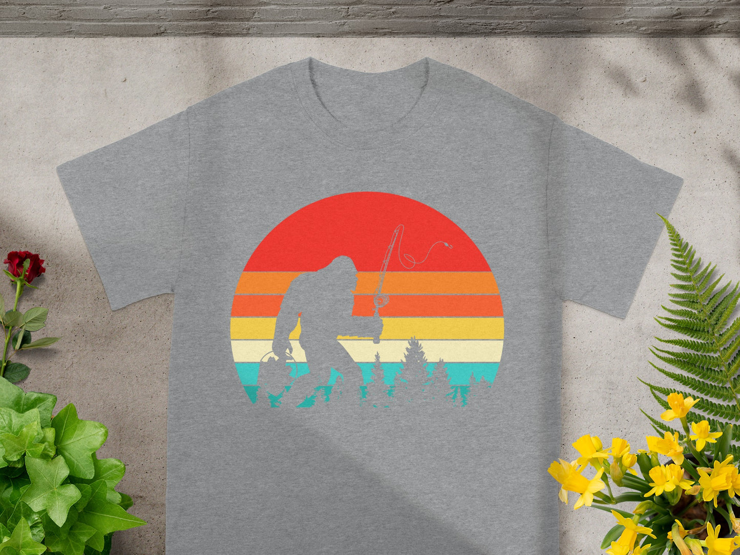 Bigfoot fishing silhouette against a retro striped sunset on a gray t-shirt.