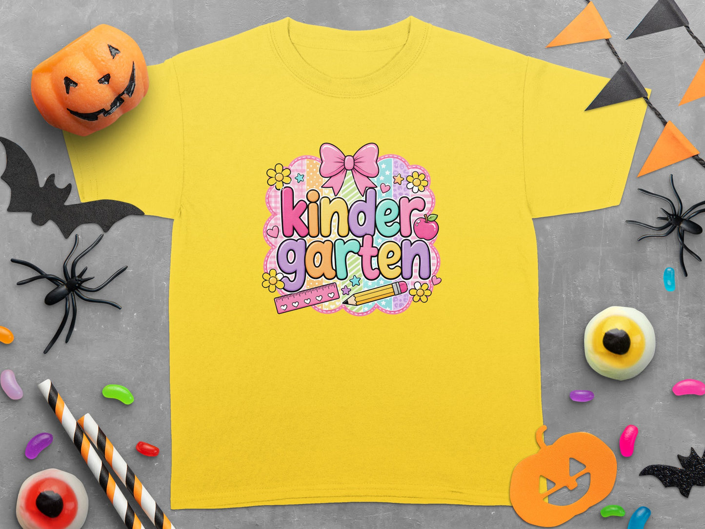 Yellow t-shirt with "kinder garten" text, playful Halloween decorations, and school supplies.