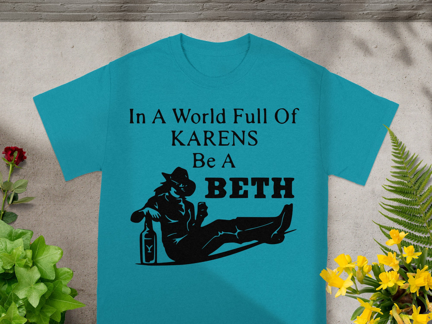 Teal t-shirt with black text "In A World Full Of KARENS Be A BETH" and silhouette.