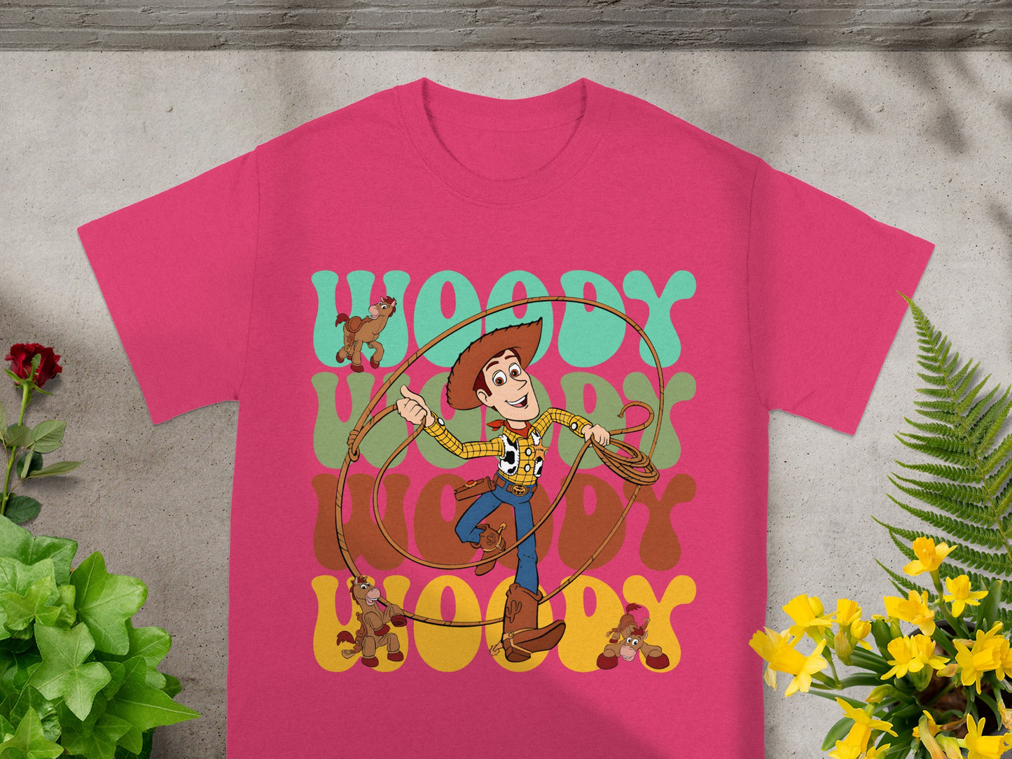Pink t-shirt with cartoon Woody and Toy Story characters on it.