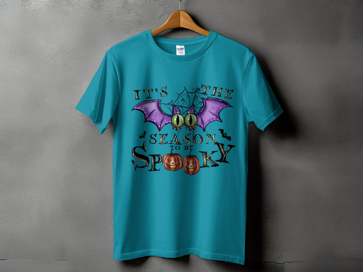 Teal t-shirt with "It's The Season To Be Spooky" Halloween graphic.