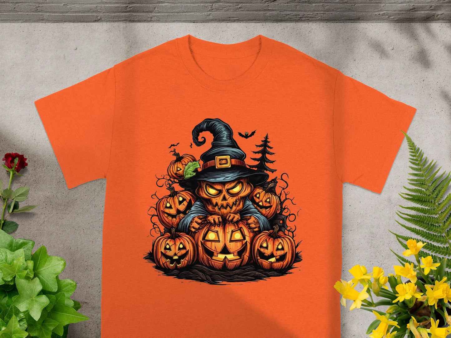 Orange t-shirt with a jack-o'-lantern character wearing a witch hat, surrounded by pumpkins.