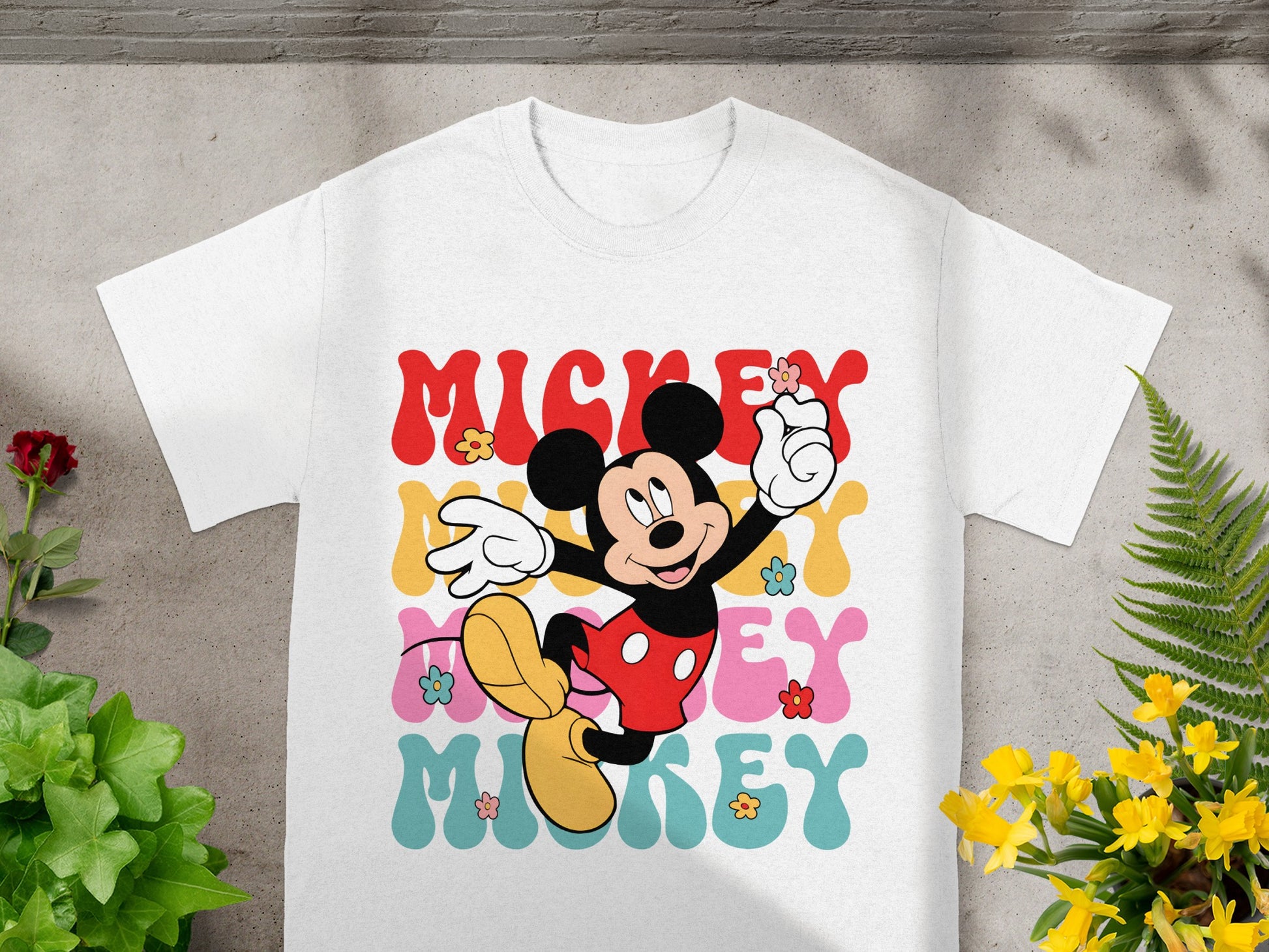 Mickey Mouse graphic with "Mickey" text and floral details on a white t-shirt.