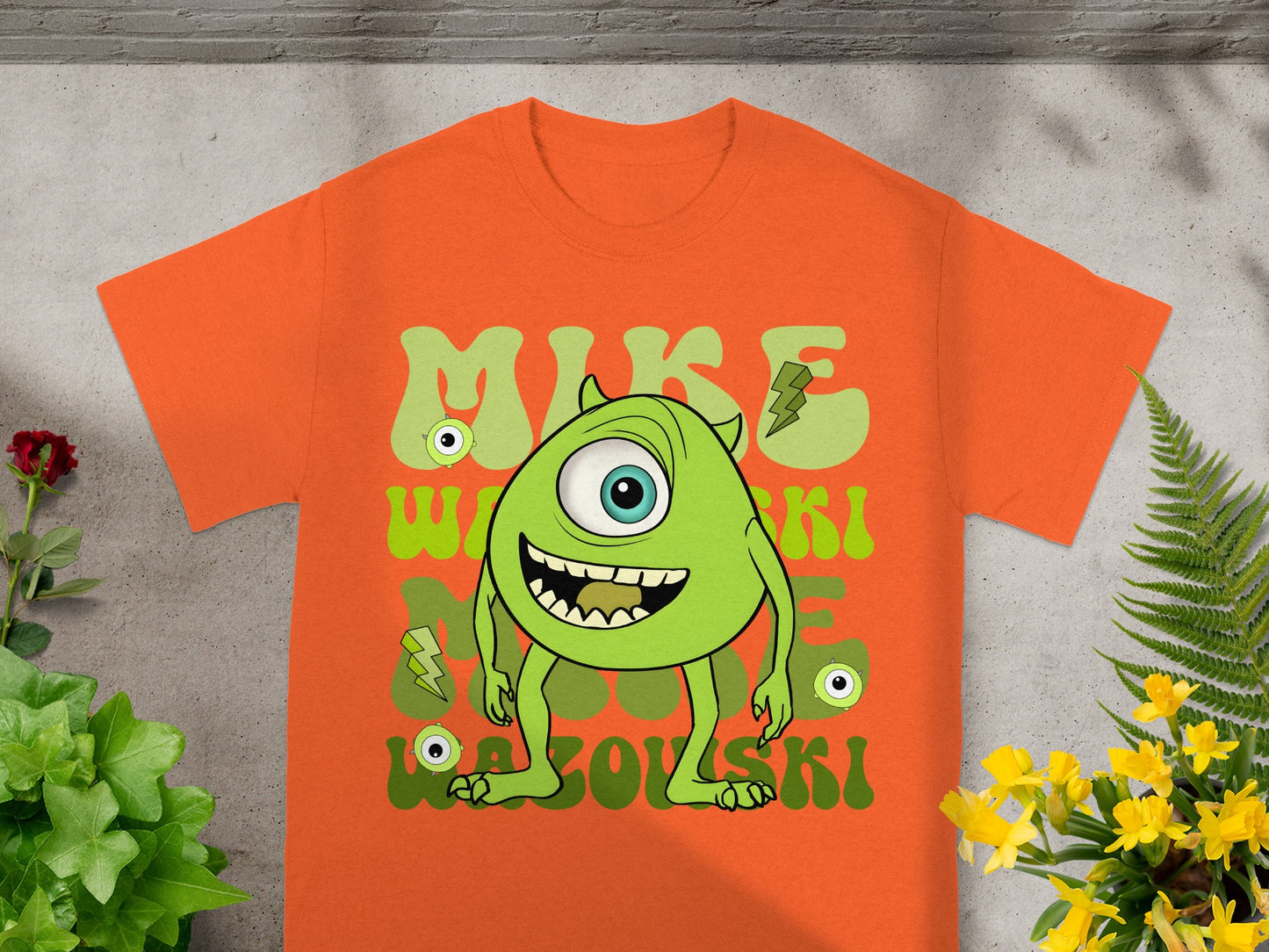 Orange t-shirt with Mike Wazowski monster graphic and text.