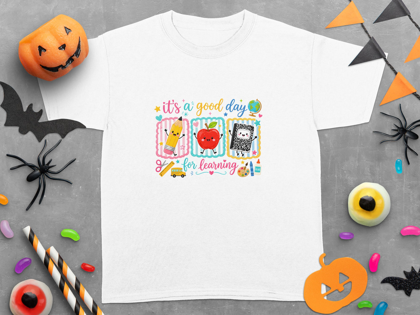 White t-shirt with graphics of a pencil, apple, and notebook saying "it's a good day for learning".