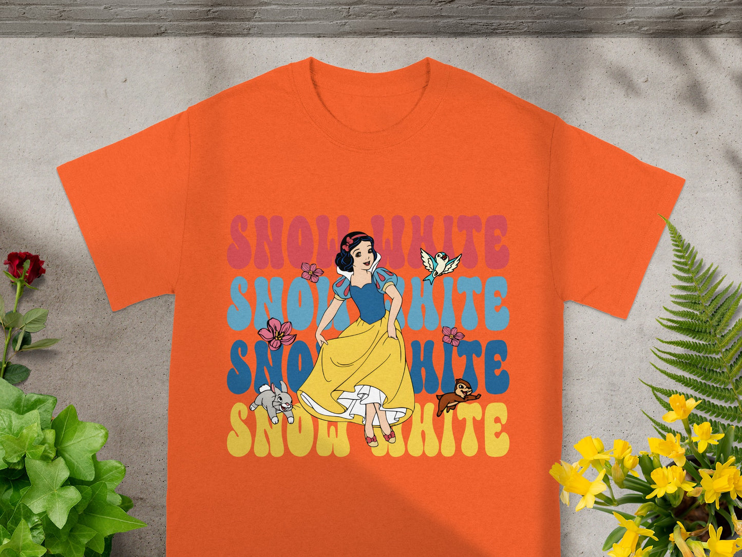 Snow White graphic on an orange t-shirt with floral accents.