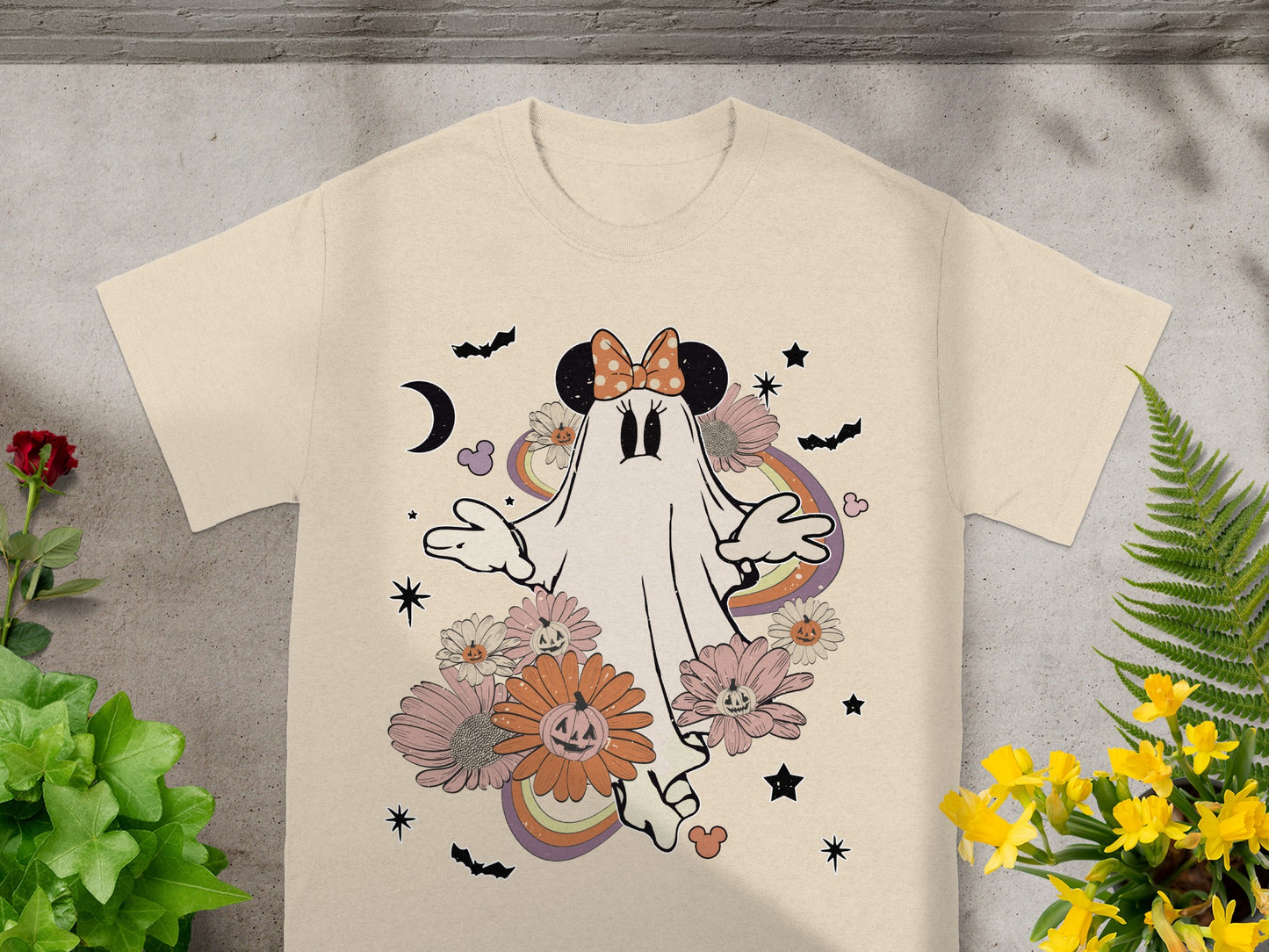 Ghost wearing Minnie Mouse ears with pumpkins and flowers, on a beige t-shirt.