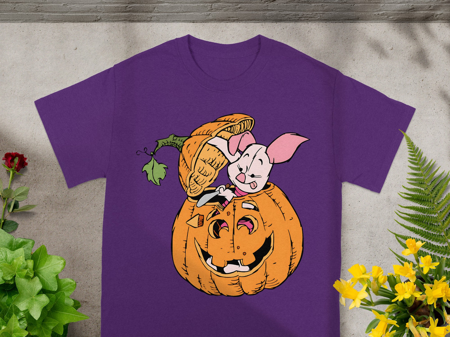 Piglet peeking out of a carved pumpkin on a purple t-shirt.
