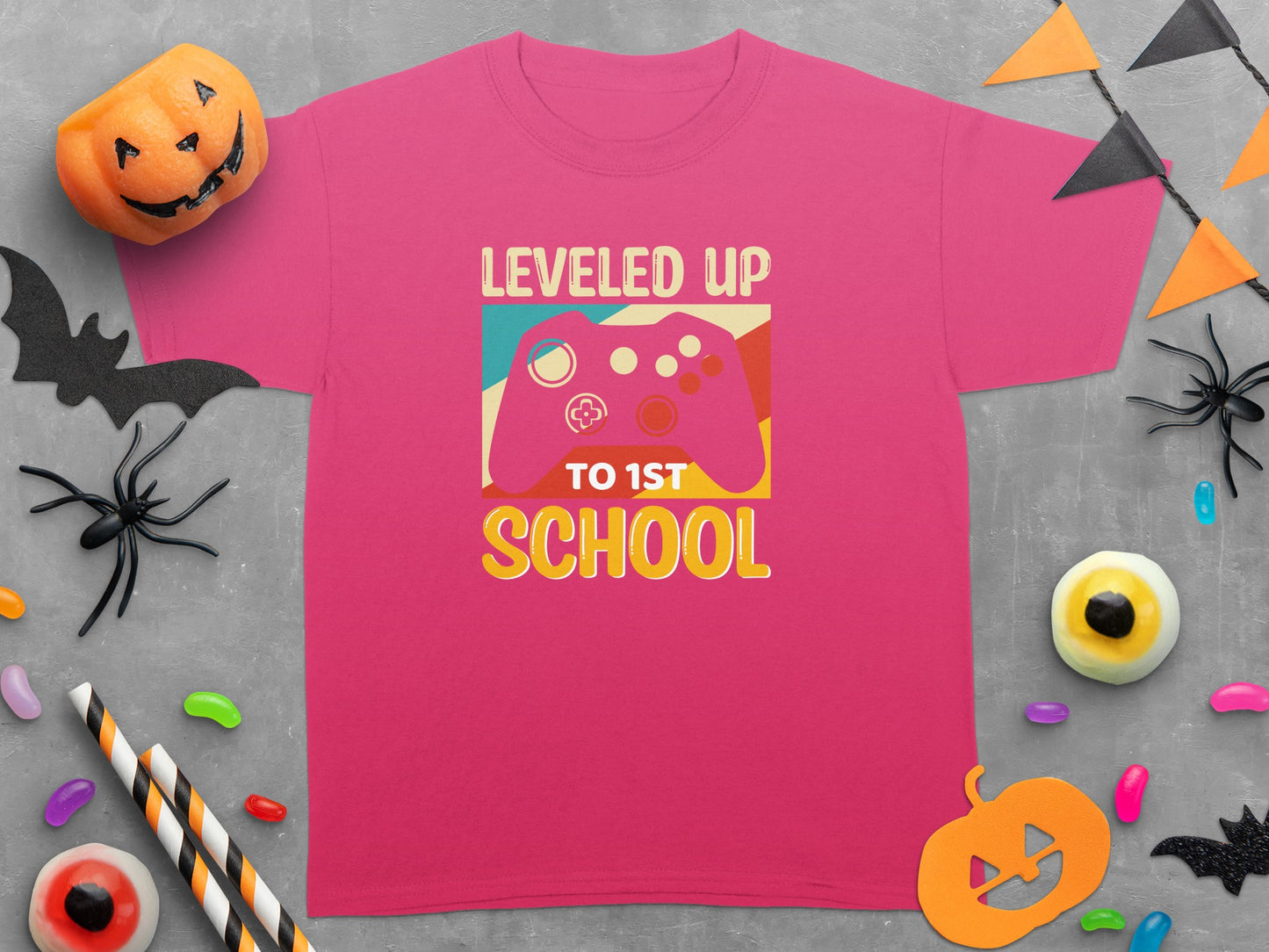 Pink t-shirt with "LEVELED UP TO 1ST SCHOOL" text and a video game controller graphic.