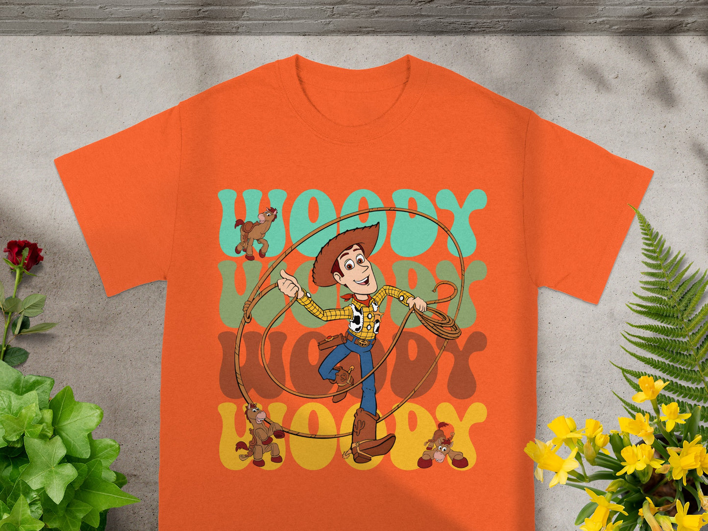 Woody from Toy Story with horses and rope on an orange t-shirt.