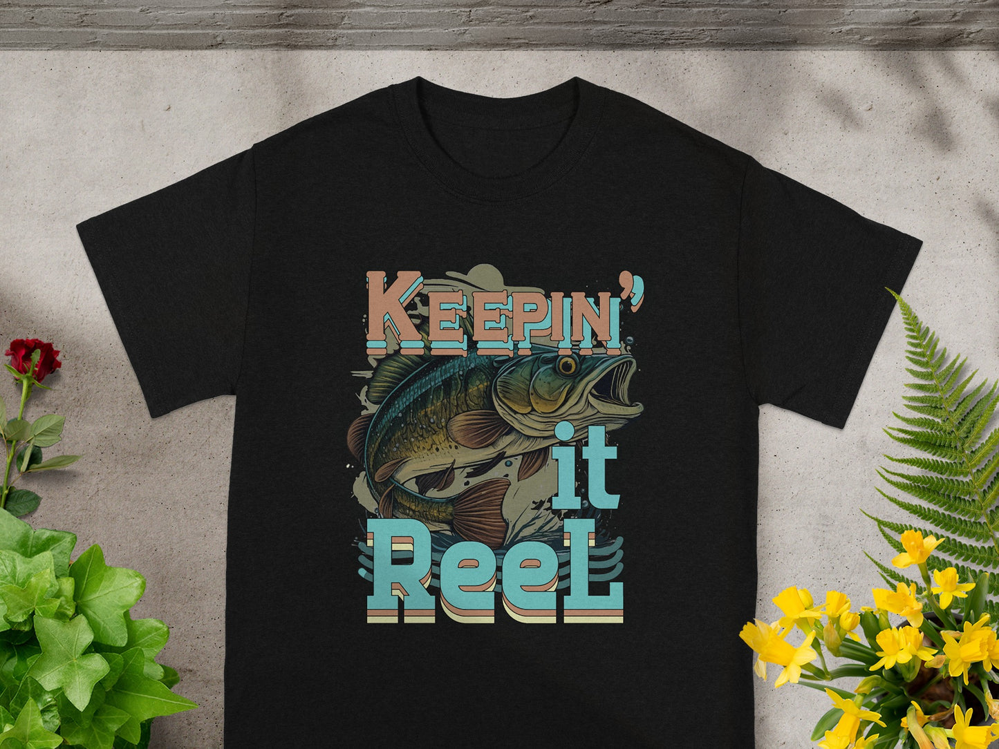 Black t-shirt with "Keepin' it Reel" text and a fish graphic.