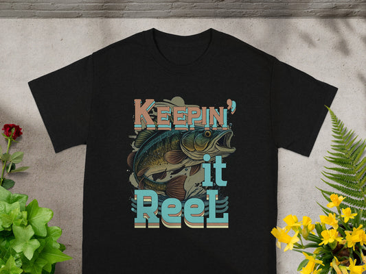Black t-shirt with "Keepin' it Reel" text and a fish graphic.