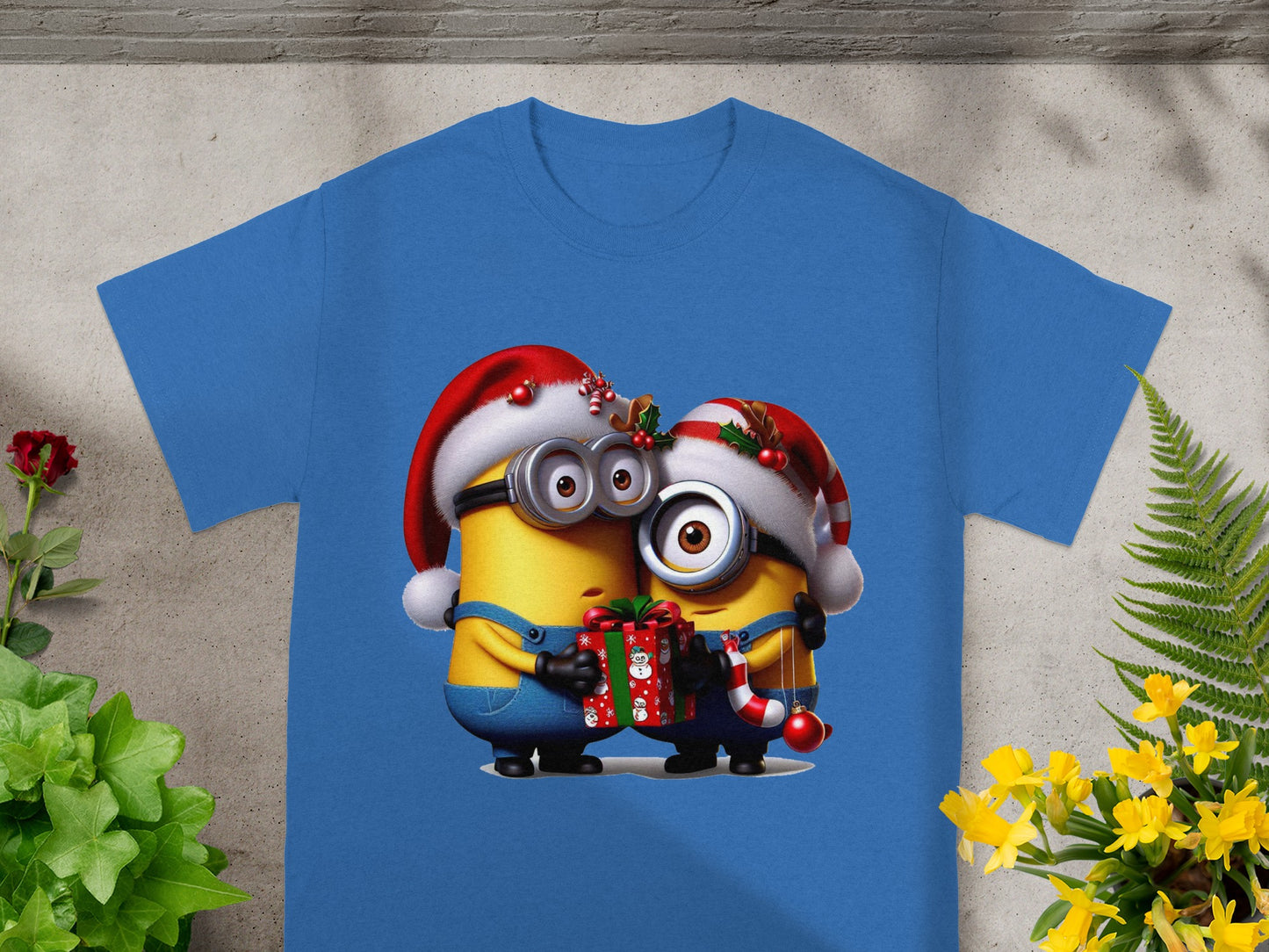 Two Minions in Santa hats share a Christmas gift and candy cane on a blue t-shirt.