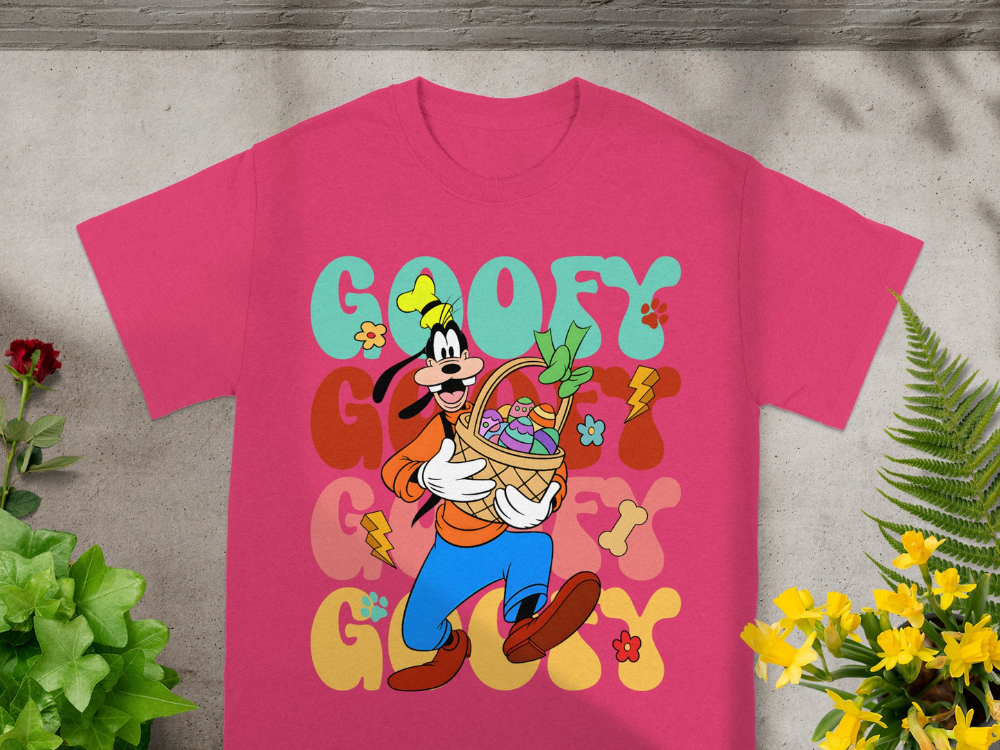 Goofy holding an Easter basket with colorful eggs and flowers, on a pink t-shirt.