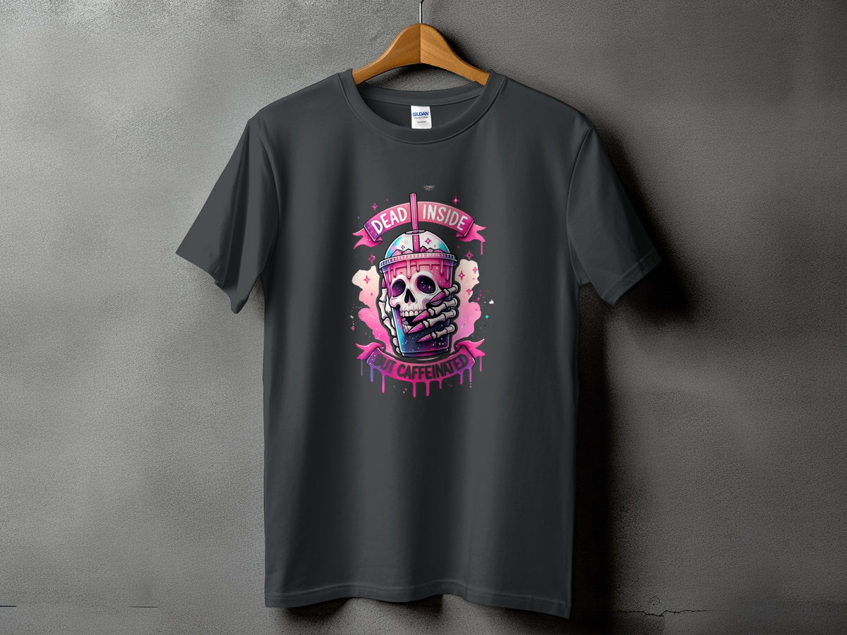 Dark gray t-shirt featuring a skull holding a pink drink with text "DEAD INSIDE BUT CAFFEINATED".