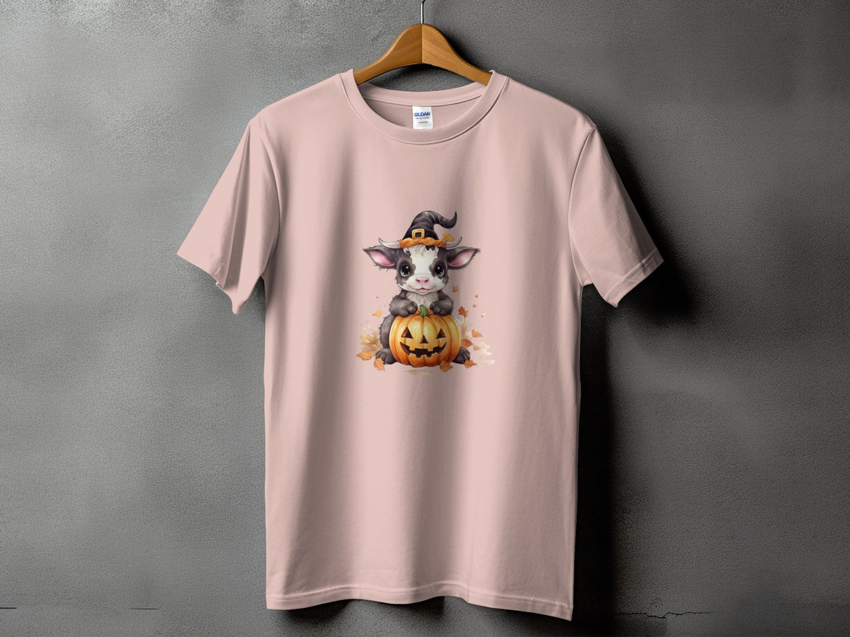 Pink t-shirt with a cartoon cow wearing a witch hat sitting on a pumpkin.