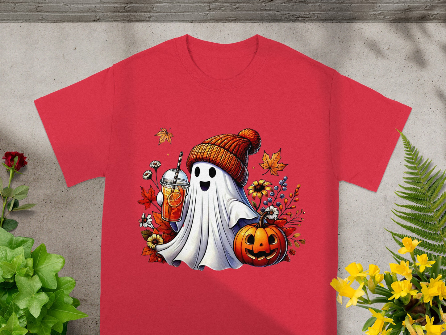 Ghost wearing beanie holds autumn drink next to jack-o'-lantern and fall leaves.