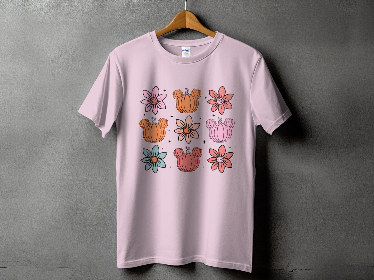 Pink t-shirt with a grid of nine illustrations featuring flowers and Mickey Mouse-shaped pumpkins.