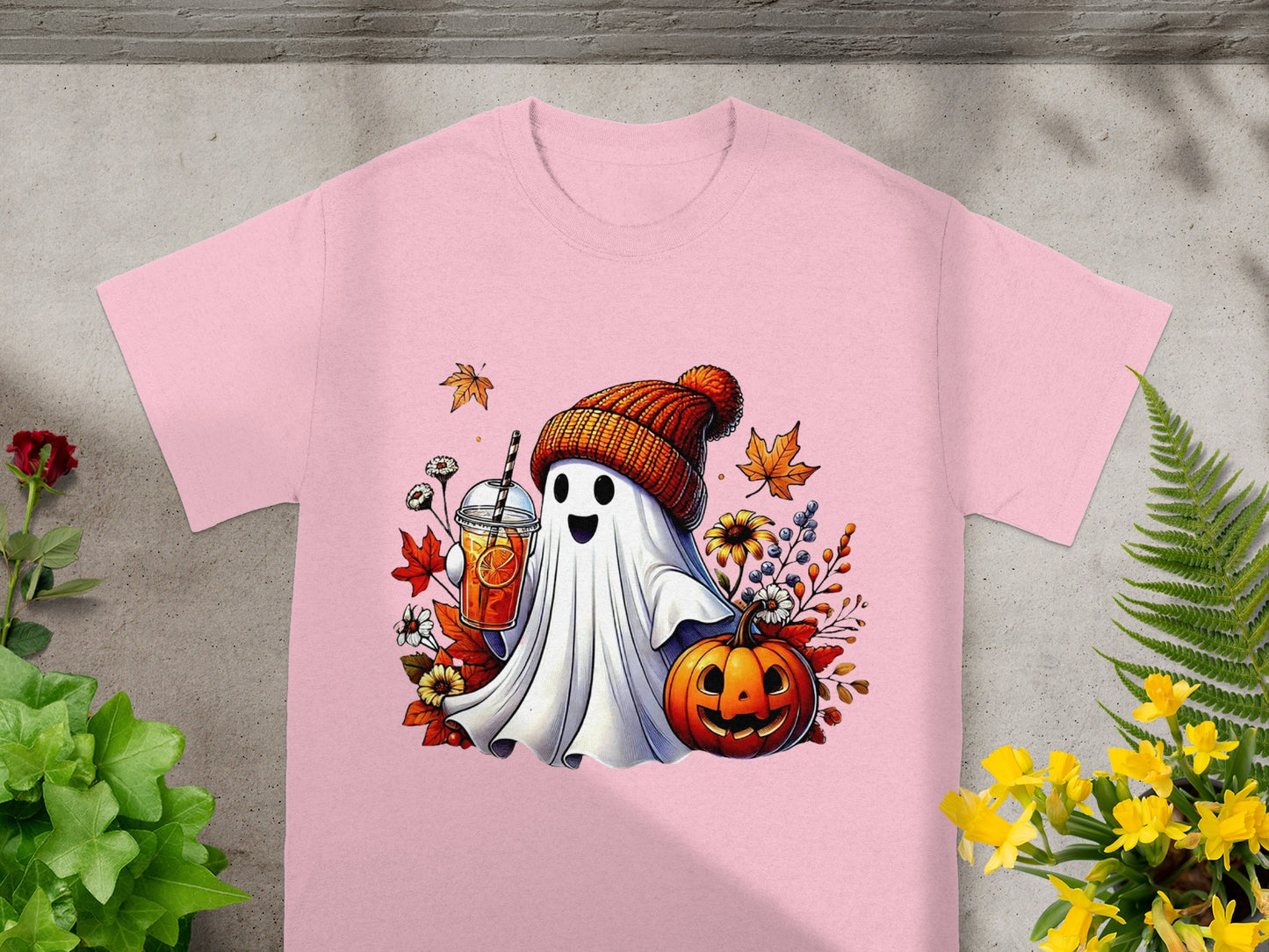 Pink t-shirt with a cheerful ghost holding a drink and standing next to a jack-o'-lantern.