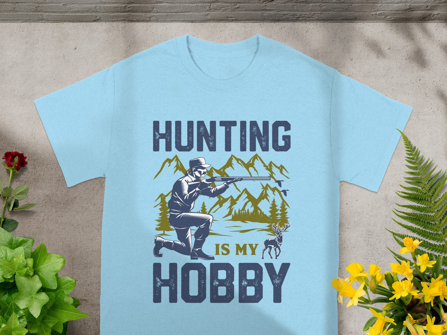 Hunting is my hobby graphic on a light blue t-shirt with a hunter, deer, and mountains.