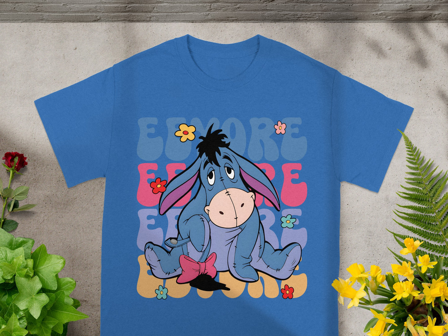 Eeyore sitting with colorful "EEYORE" text and flowers.