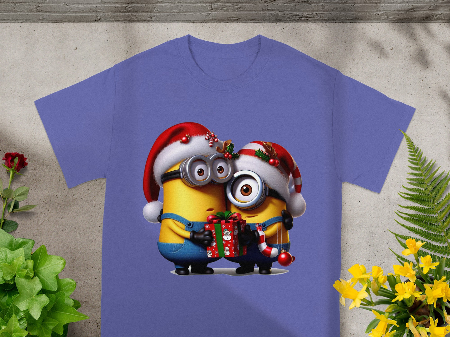 Two Minions in Santa hats hold a gift and candy cane on a purple t-shirt.