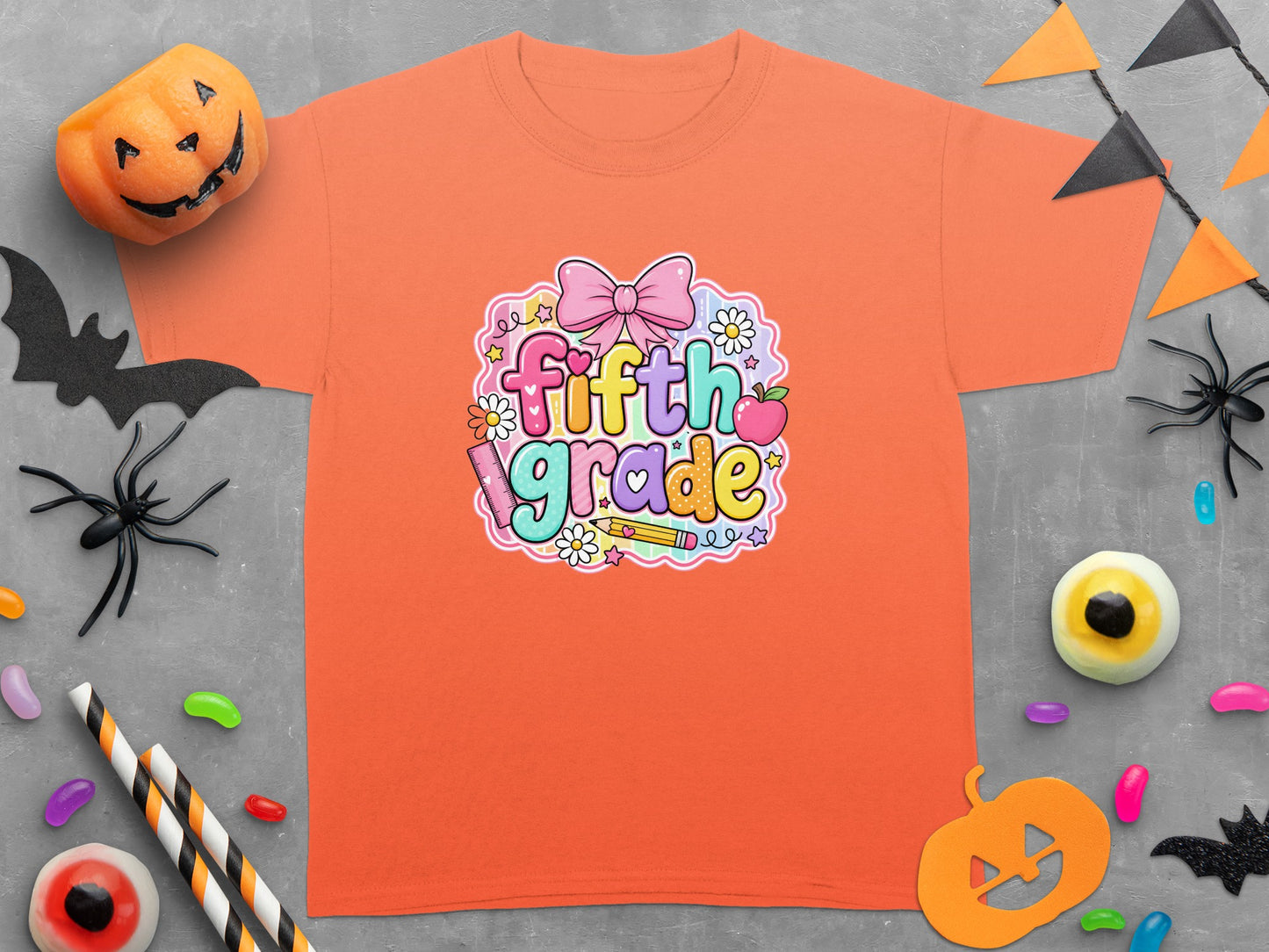 Orange t-shirt with colorful "fifth grade" text surrounded by a bow, apple, flowers, pencil, and ruler.