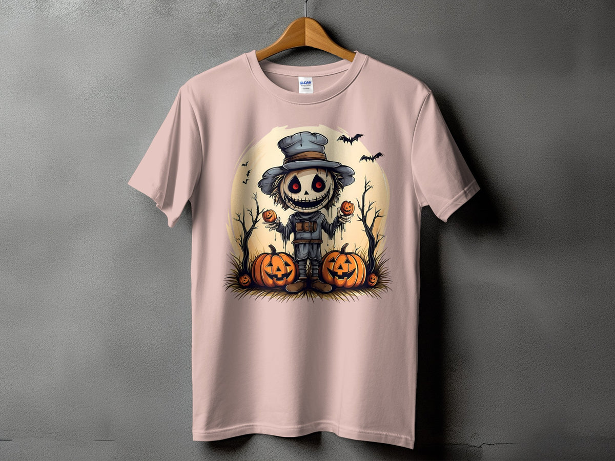 Pink t-shirt with a cartoon scarecrow holding pumpkins and bats, set against a pale moon.