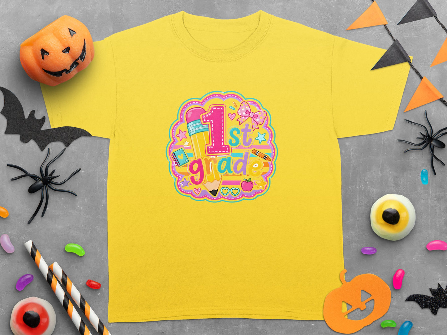 Yellow t-shirt with "1st grade" graphic featuring school supplies and Halloween decorations.