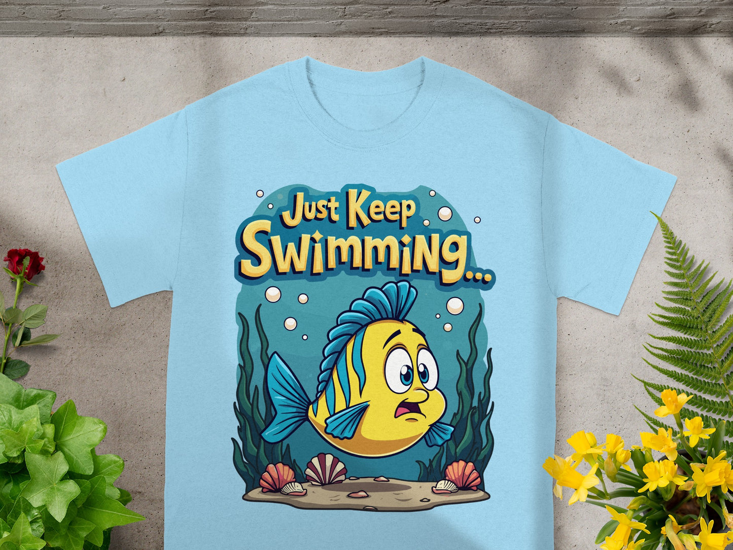 Light blue t-shirt with a cartoon yellow fish and "Just Keep Swimming..." text.