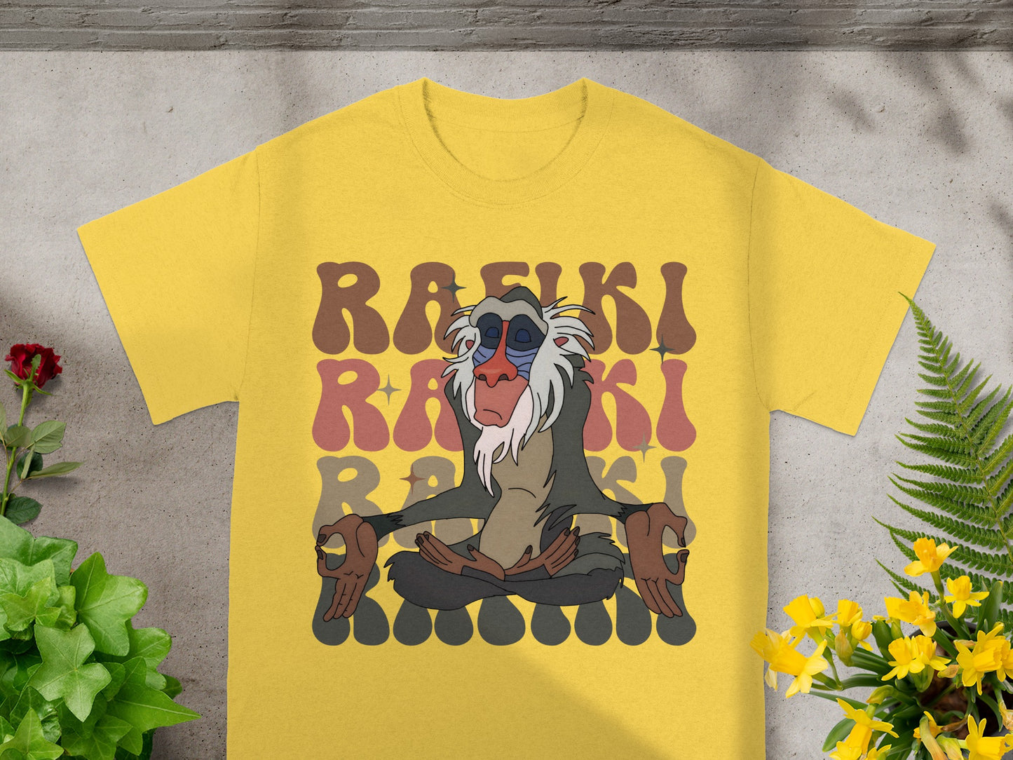 Rafiki meditating on a yellow t-shirt with colorful text.