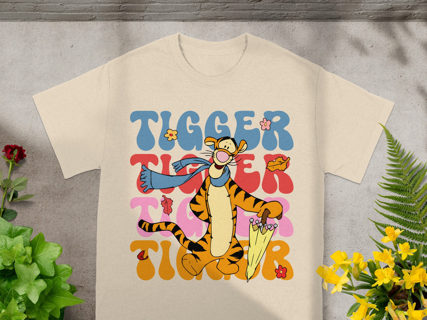 Tigger from Winnie the Pooh character on a cream t-shirt with colorful wavy text.