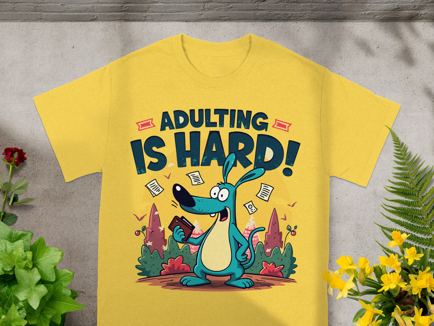 Yellow t-shirt graphic of a cartoon dog holding a wallet with "ADULTING IS HARD!" text.