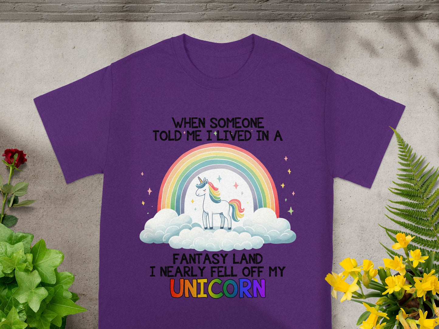 Purple t-shirt with text and unicorn illustration on clouds with rainbow.