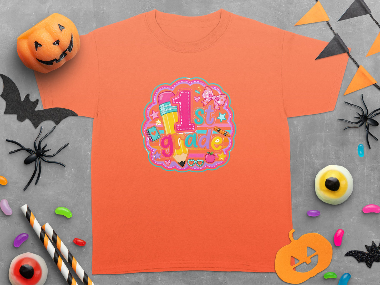 Orange t-shirt with a "1st grade" graphic, featuring a pencil, bow, and school supplies.
