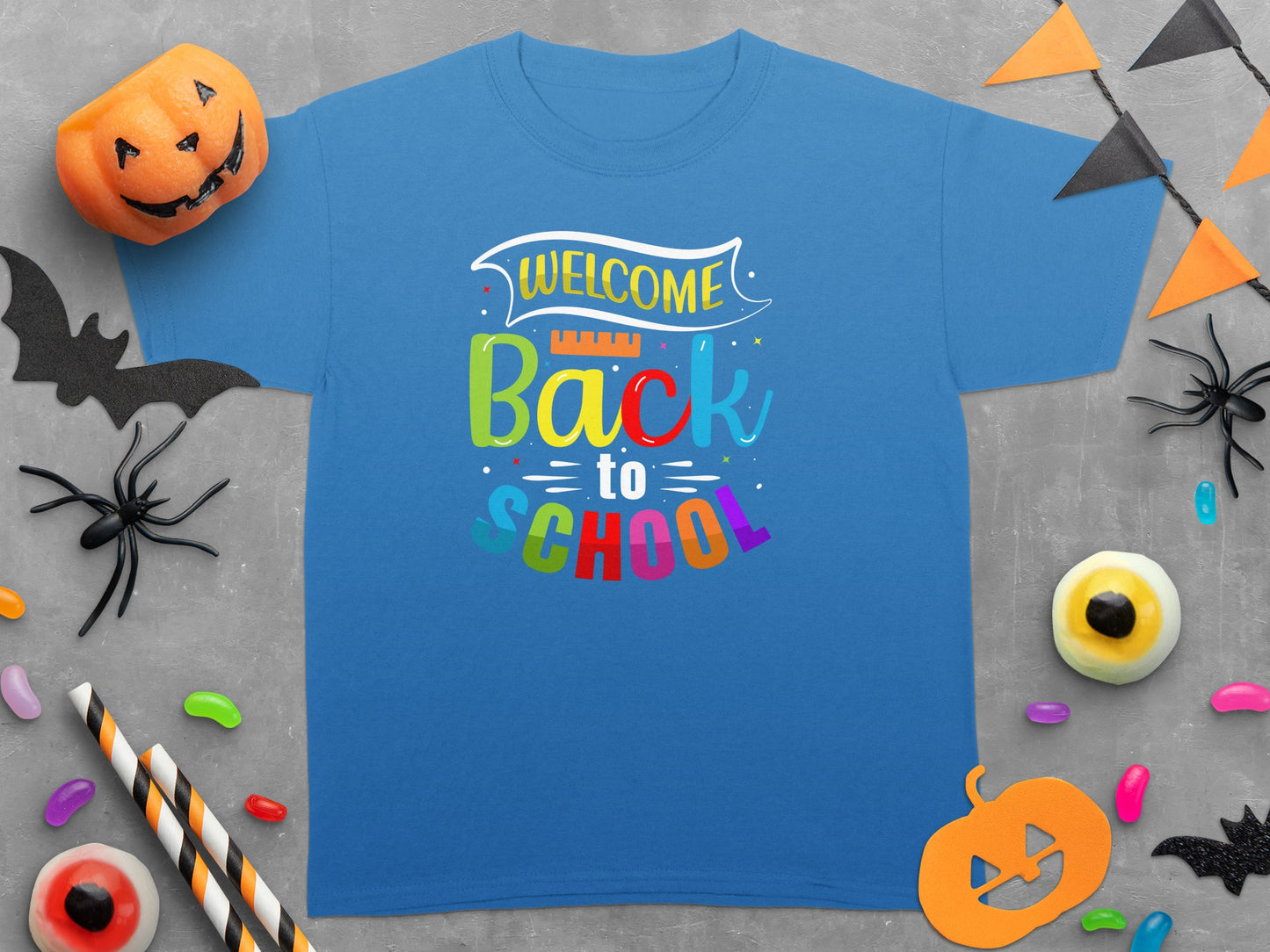 Blue t-shirt with "Welcome Back to School" graphic, surrounded by Halloween decorations.