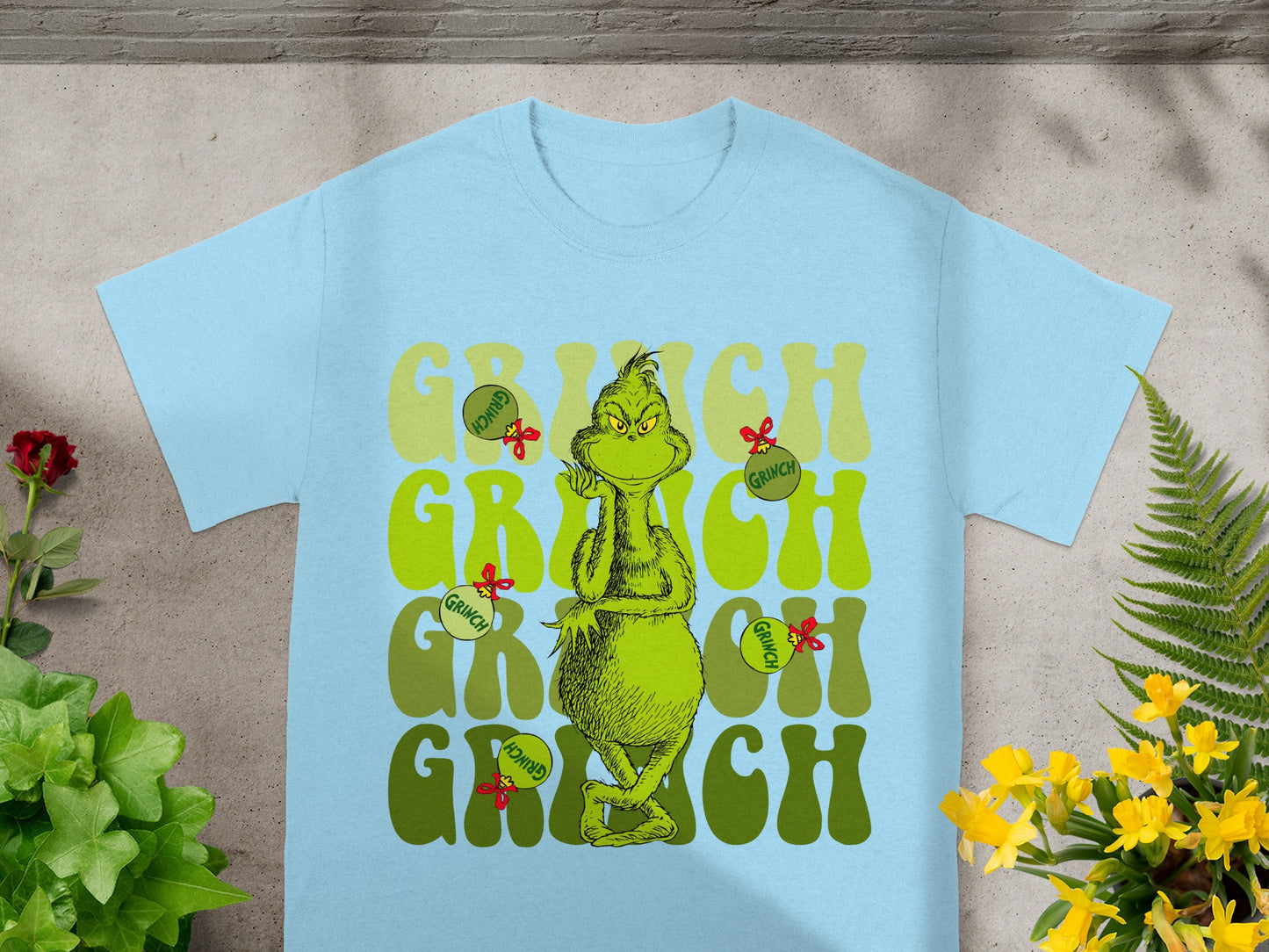 Light blue t-shirt with repeating "Grinch" text and cartoon Grinch character.