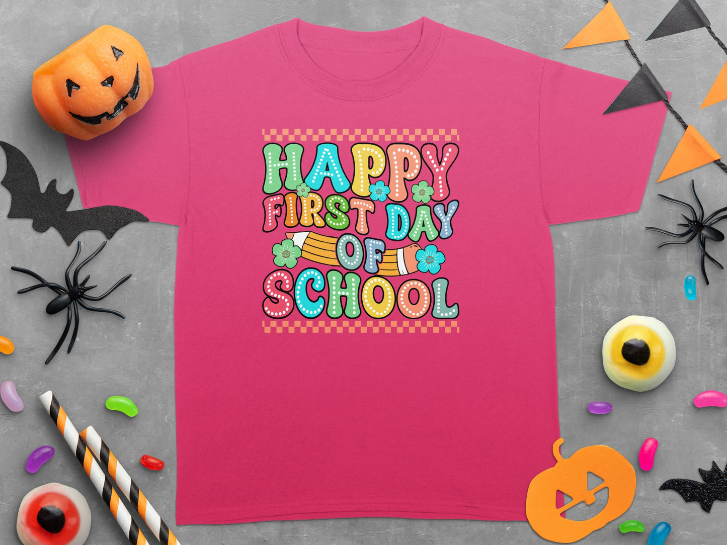 Pink t-shirt with "Happy First Day Of School" text and Halloween decorations.