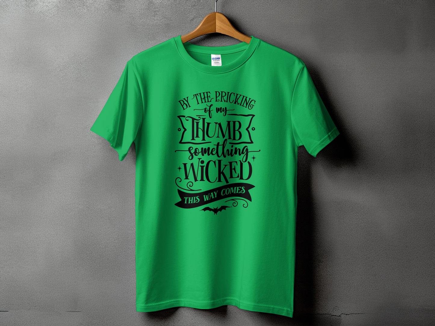 Green t-shirt with black text "By the pricking of my thumb, something wicked this way comes".