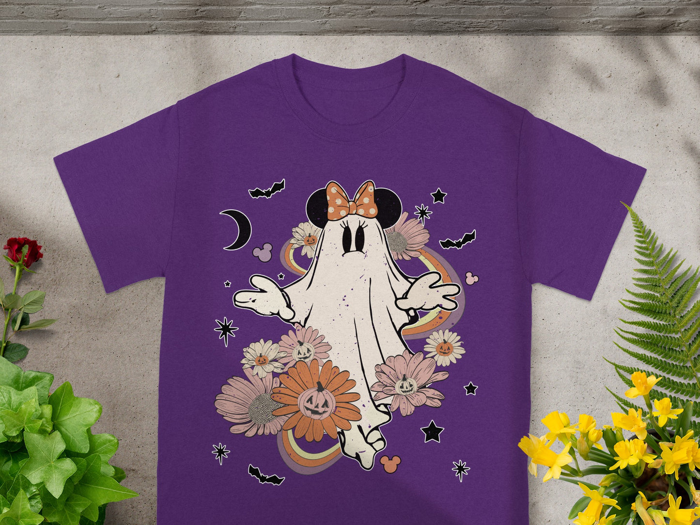 Purple t-shirt with a ghost wearing a bow, surrounded by flowers and Halloween elements.
